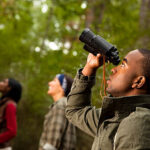 Group of friends camping and hiking using binoculars