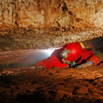 Narrow cave passage with a spelunker explorer