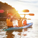 Happy family is walking at sunset sea by kayak or canoe. Active tourism concept