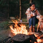 Woman and beagle dog warm near the campfire