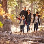 Happy Hispanic family with two children walking in a forest