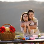 10 Best Picnic Gift Baskets for Couples Young couple smiling, hugging and enjoying a romantic picnic in nature.
